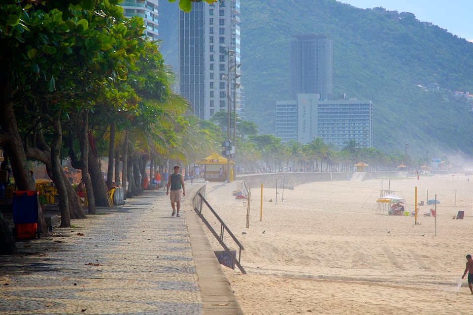 Ein Strand mit Palmen, einem sandigen Ufer und Gebäuden im Hintergrund.