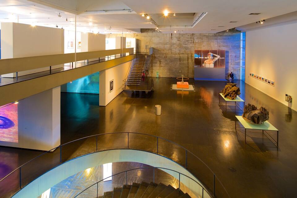 An art gallery with a staircase, artwork on display, and a blue wall.