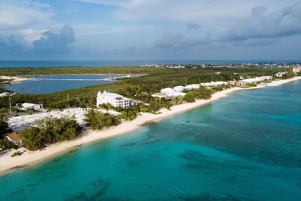 Un pueblo costero con playa, aguas turquesas cristalinas y abundante vegetación.