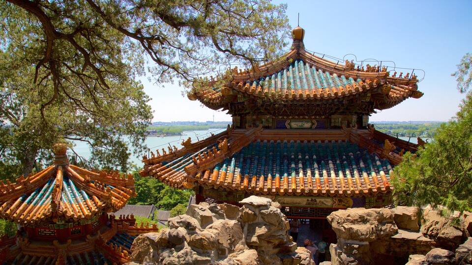 A traditional Chinese pavilion with ornate roofs and a scenic view of a river and city skyline in the background.
