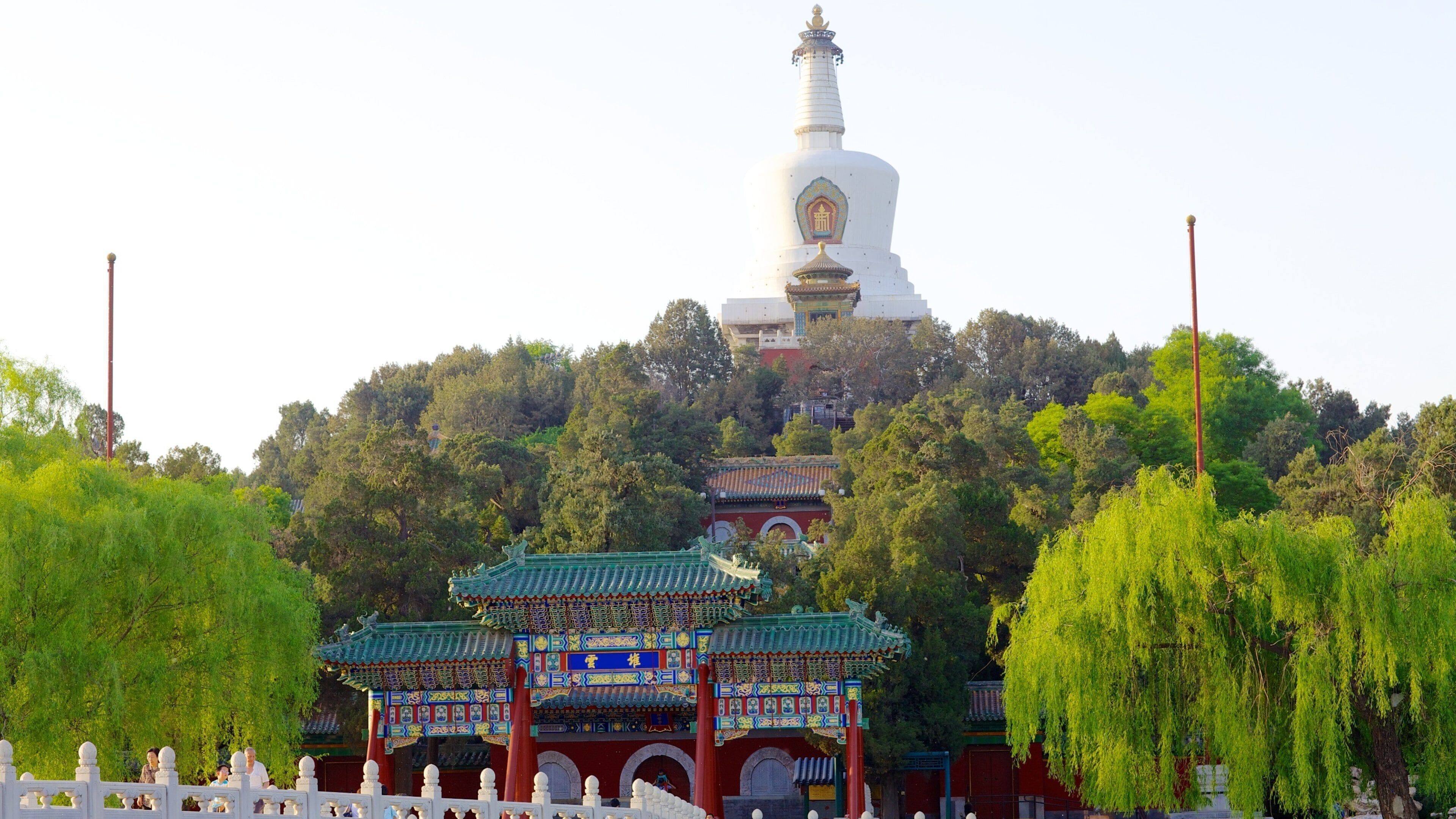 Un tempio cinese tradizionale con una grande stupa bianca, circondato da vegetazione lussureggiante e un padiglione con tetto rosso.
