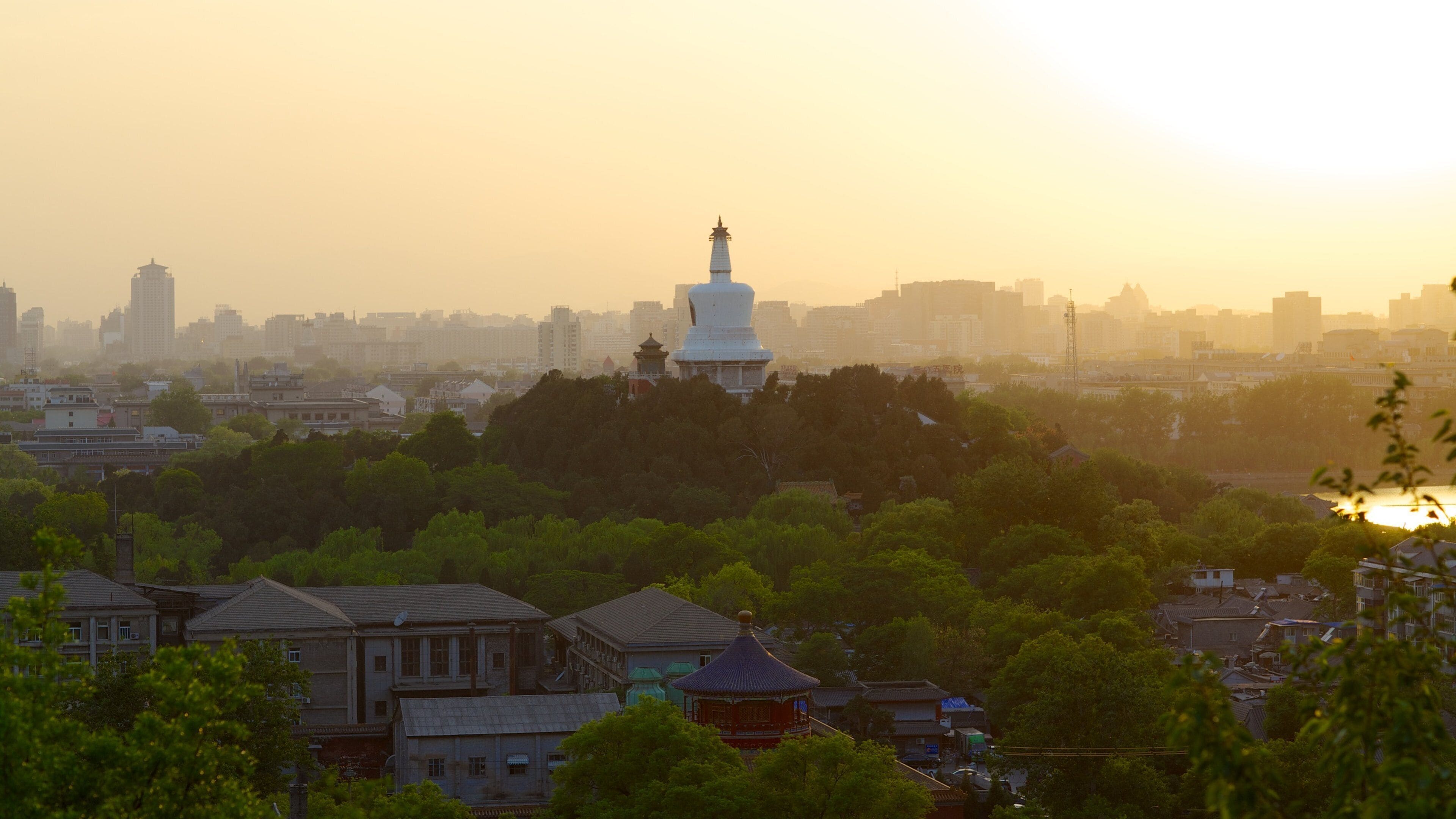 A cityscape with a prominent white pagoda-like structure amidst residential buildings and greenery.