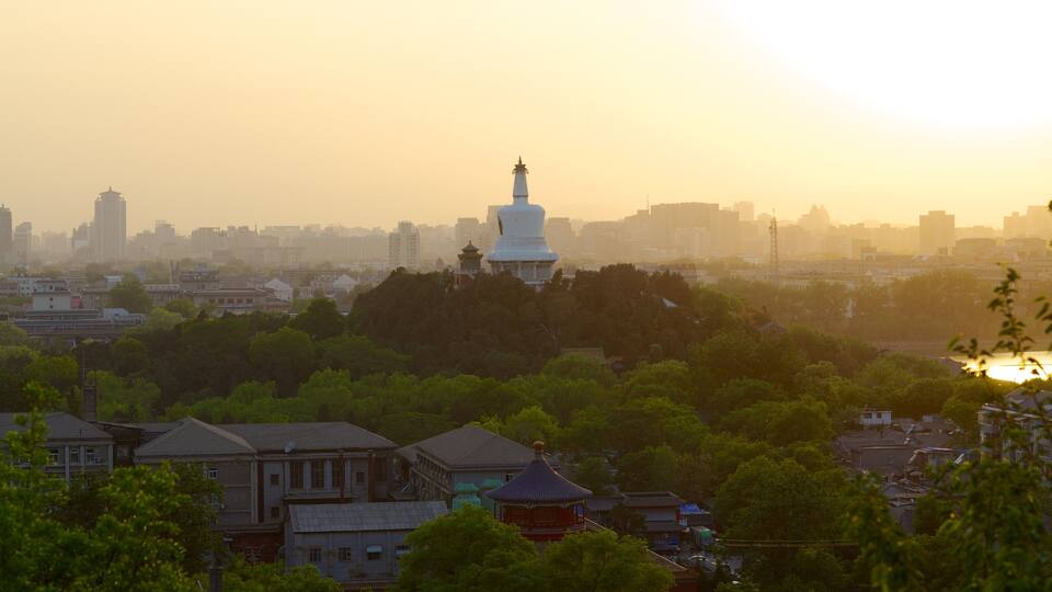 A cityscape with a prominent white pagoda-like structure amidst residential buildings and greenery.