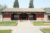A traditional Chinese building with ornate red and green decorations, a tiled roof, and a central entrance with a black door.