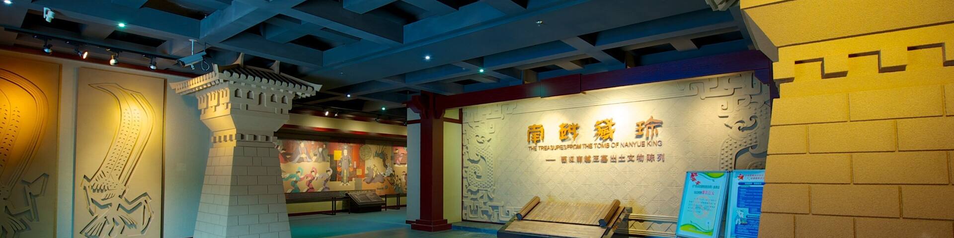 A museum interior with exhibits, including a large wall with Chinese characters and a display case.