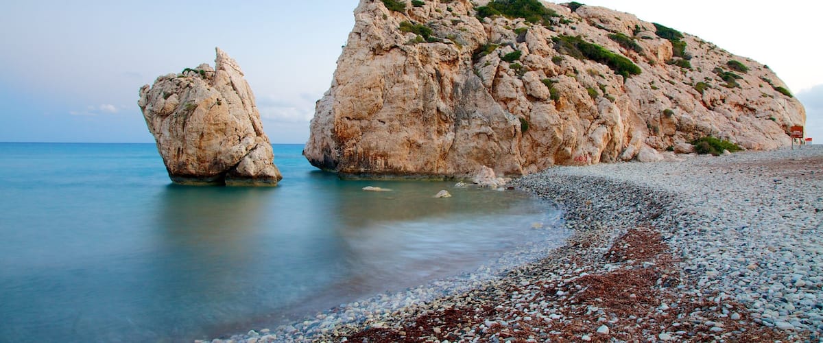 A rocky coastline with a large rock formation and a smaller rock in the water.