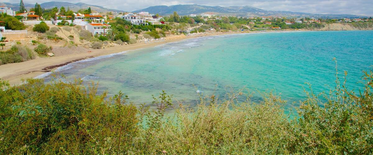 A coastal landscape with turquoise waters, sandy beaches, and residential buildings.