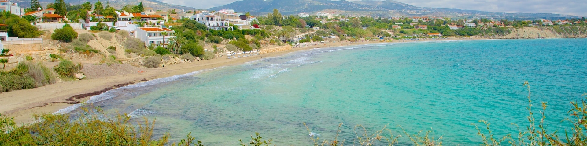 A coastal landscape with turquoise waters, sandy beaches, and residential buildings.