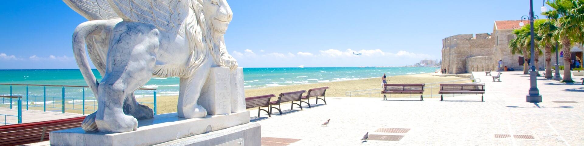 Strand von Finikoudes welches beinhaltet allgemeine Küstenansicht und Statue oder Skulptur