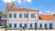 A white building with blue shutters and a red tiled roof.