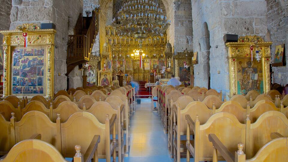 An ornate church interior with rows of wooden pews, a central altar, and a large chandelier.