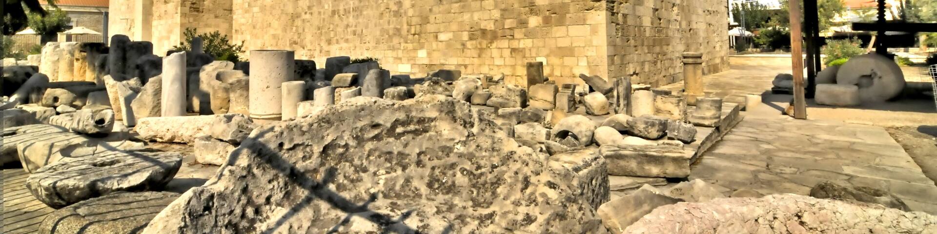 A large stone building with a flat roof and a surrounding area of scattered stone blocks and ruins.