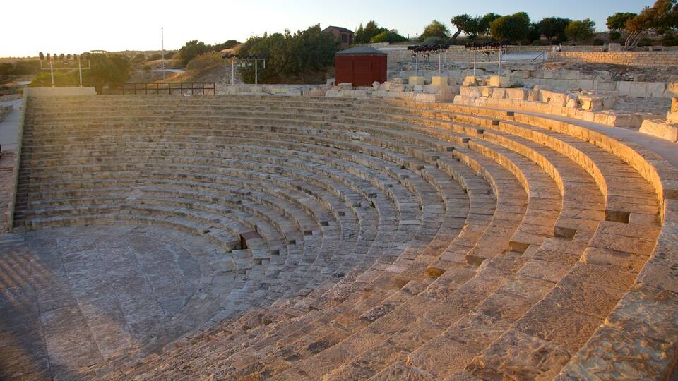 An ancient stone amphitheater with tiered seating and a small stage area.