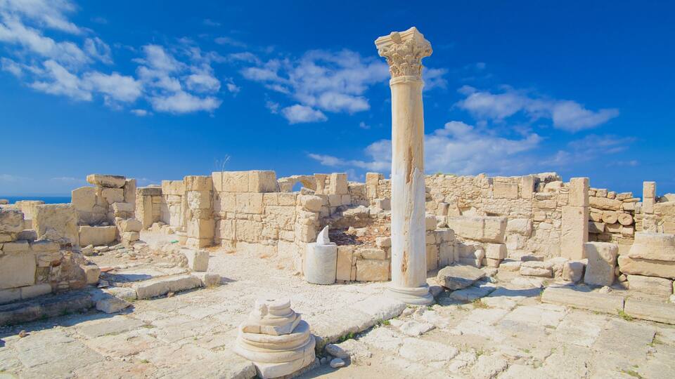 Ancient ruins with stone columns and scattered stone blocks under a clear blue sky.