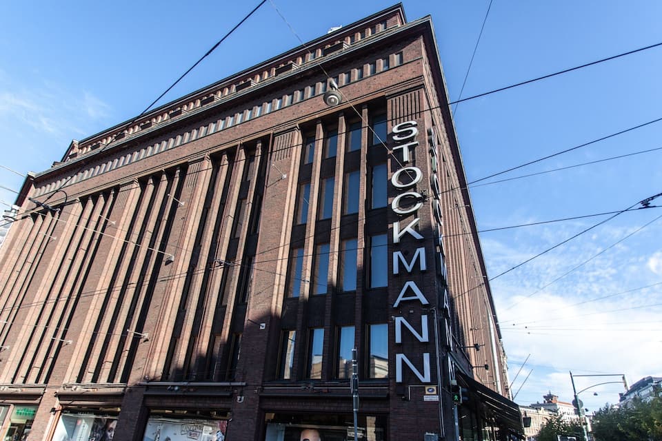 En høj murstensbygning med vertikale linjer og ordet "STOCKMANN" på facaden.