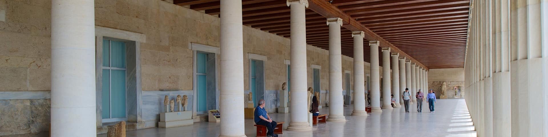 A covered colonnade with white columns and a wooden ceiling.