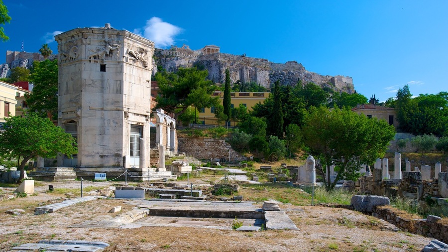 Ancient ruins with a prominent stone tower, a large rock formation in the background, and surrounding greenery.