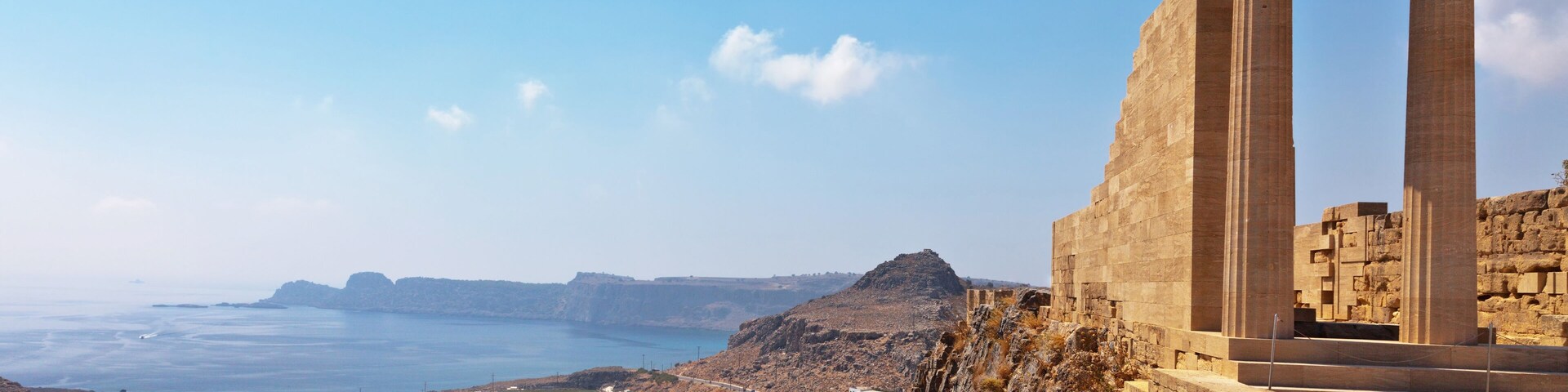 Greece. Rhodes. Acropolis of Lindos. Doric columns of the ancient Temple of Athena Lindia the IV century BC and the bay of St. Paul