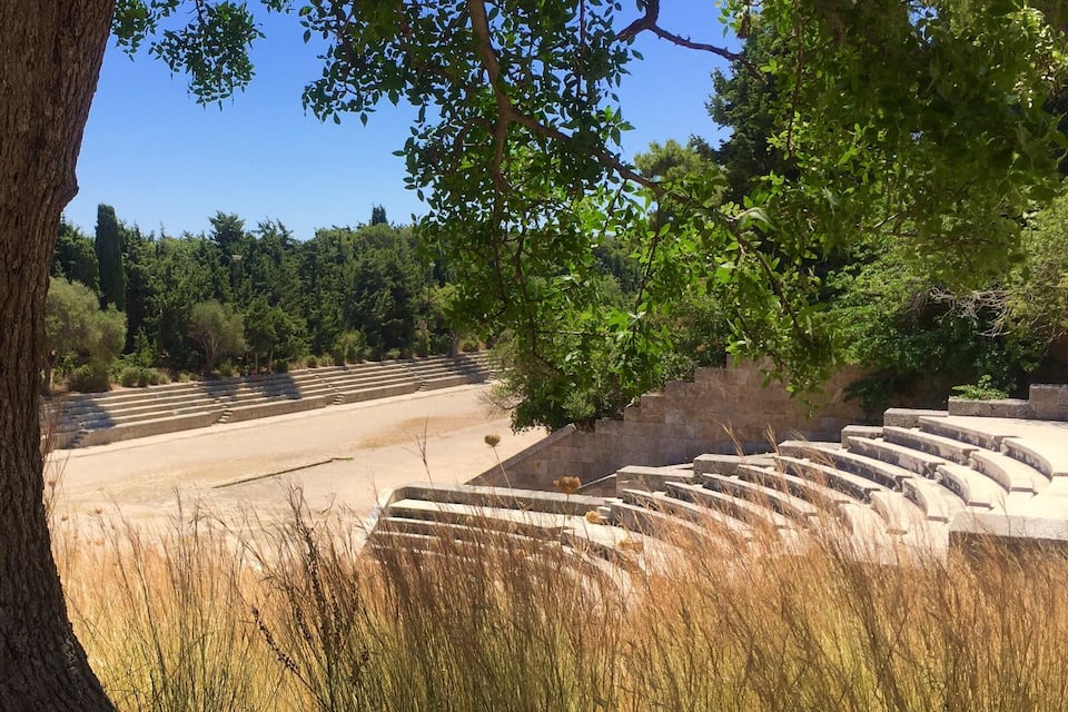 A stone amphitheater surrounded by trees and dry grass.