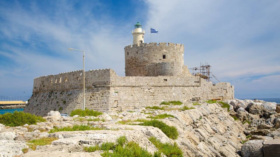 A historic stone fortress with a lighthouse, a flag, and rocky terrain.