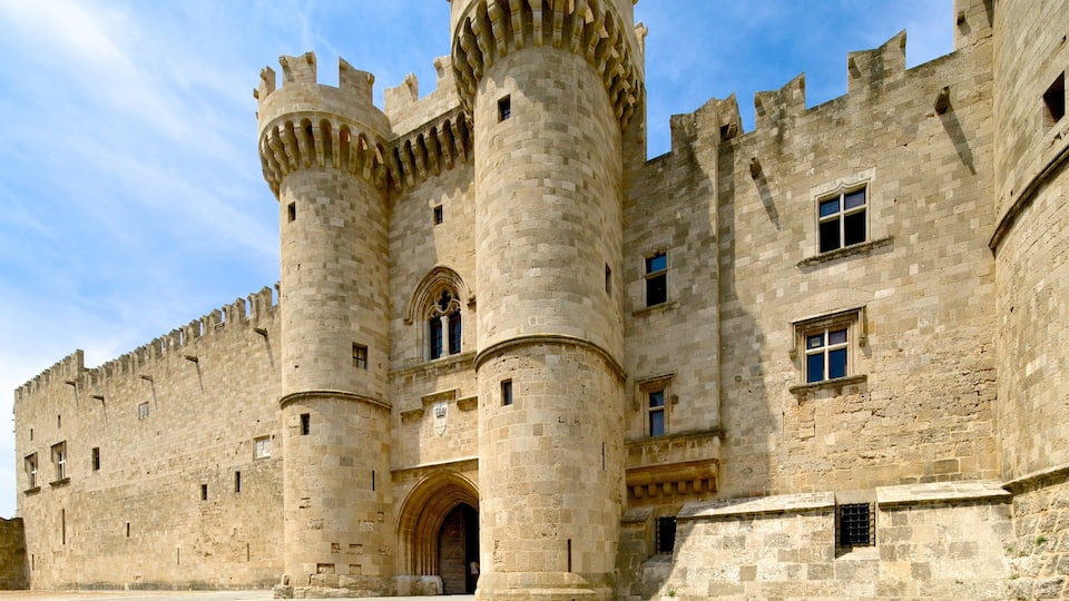 A historic stone castle with two prominent towers, arched windows, and a large entrance.