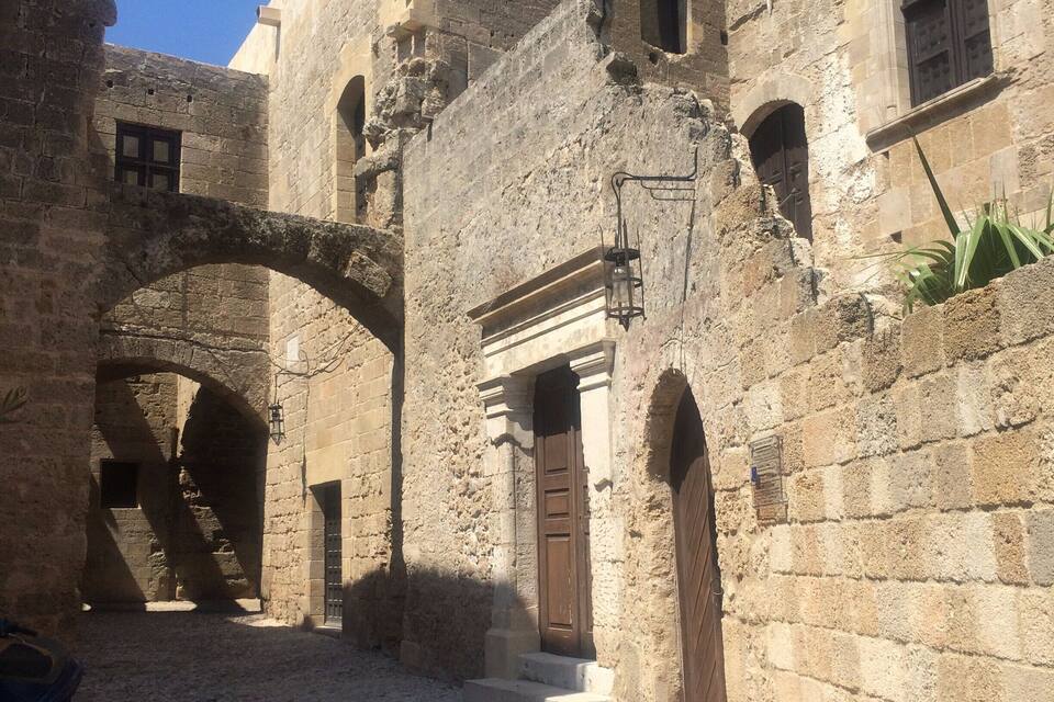 Un edificio antiguo de piedra con puertas de arco y un patio empedrado.