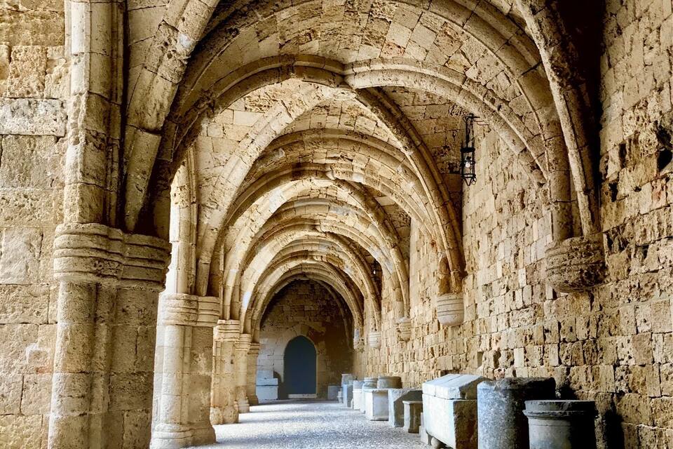An arched corridor with stone columns and a tiled floor.
