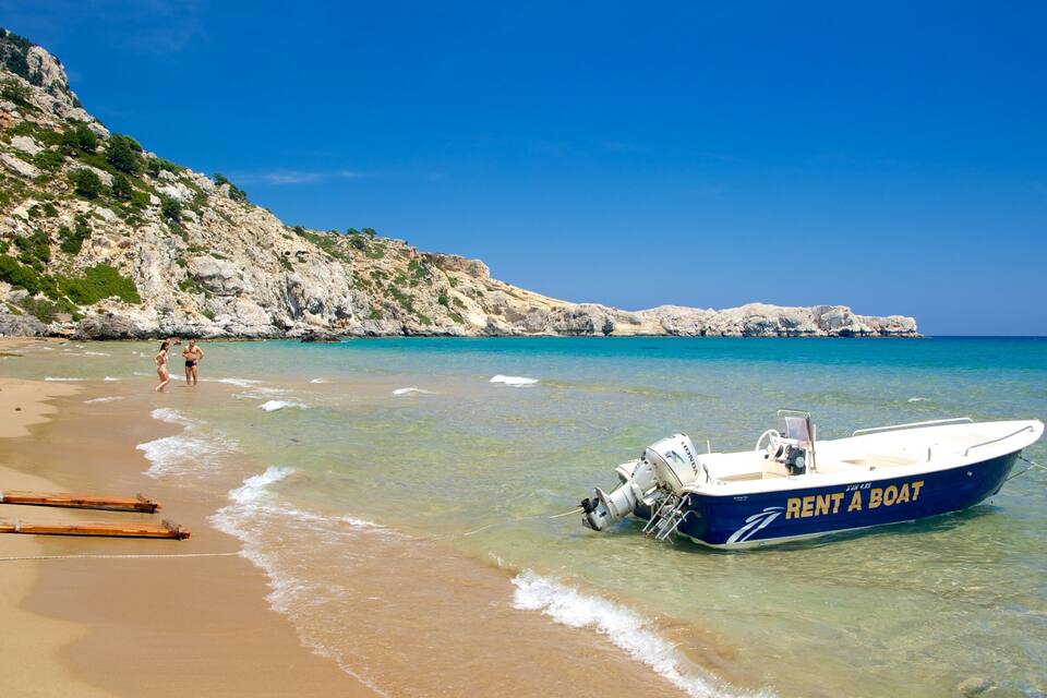 A beach with a boat labeled "RENT A BOAT" anchored in shallow water, a rocky cliff in the background, and people walking along the shore.