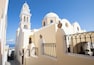 A white church with a bell tower and a dome, set against a clear blue sky.