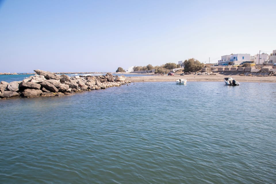 Calm waters, rocky breakwaters, and buildings along the shore.