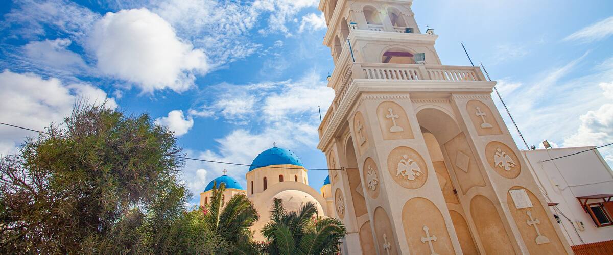 A church with a tall bell tower and blue domes.