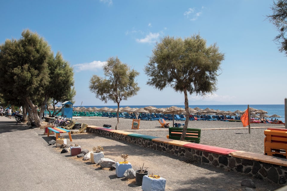 A beach with stone walls, colorful benches, and umbrellas.