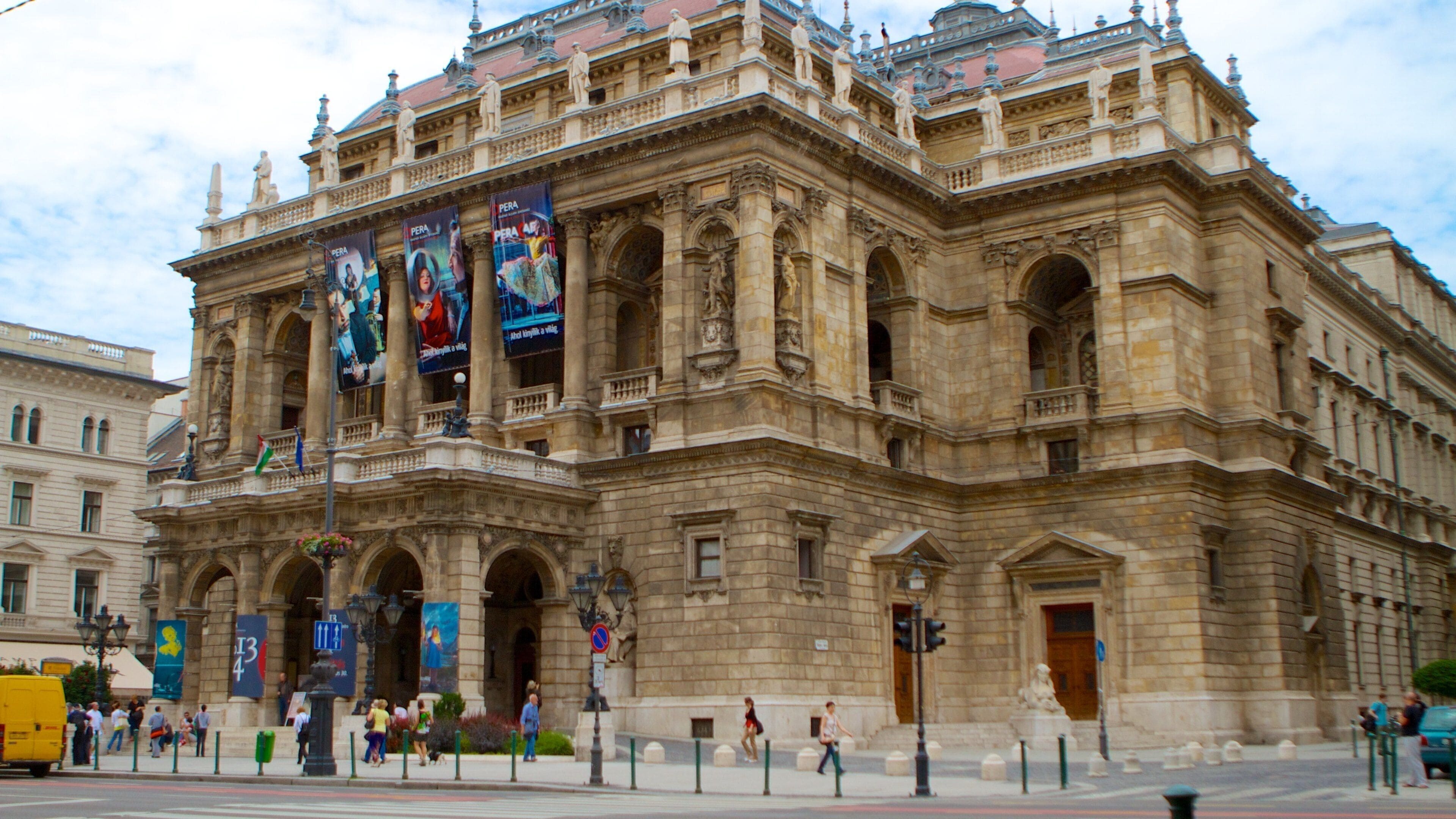 A historic building with ornate architecture, large banners, and a busy street scene.