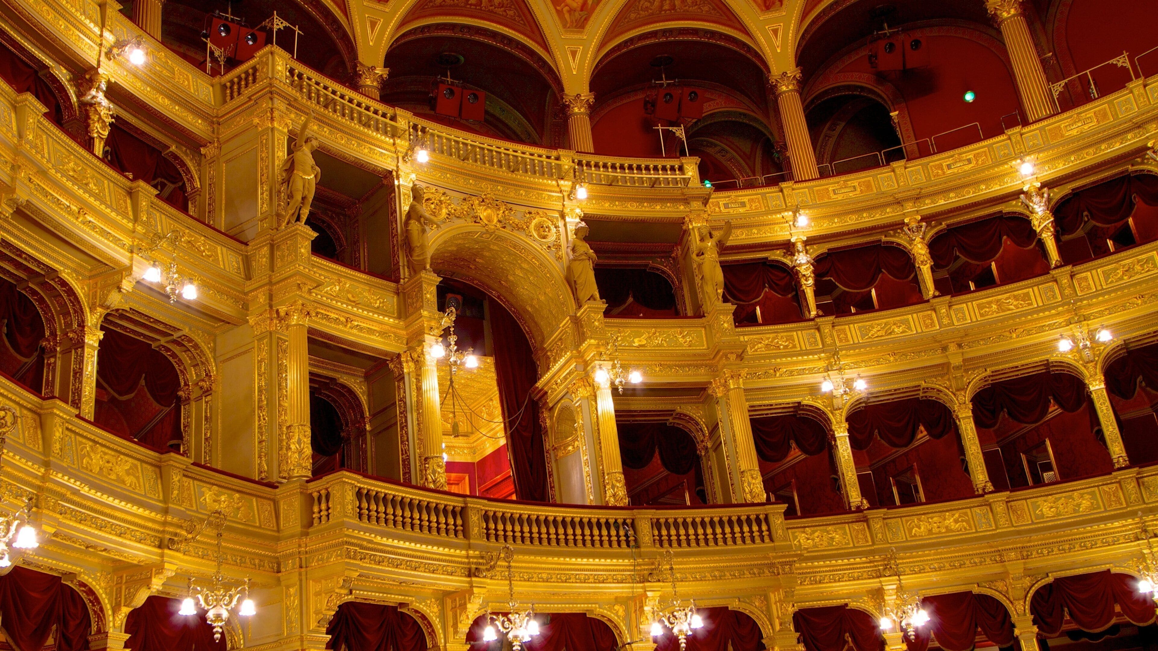 An ornate theater with golden balconies and red curtains.