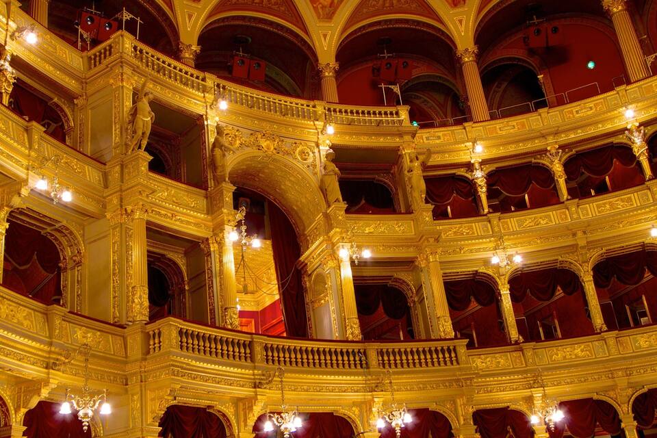 Un teatro ornamentado con balcones dorados y cortinas rojas.