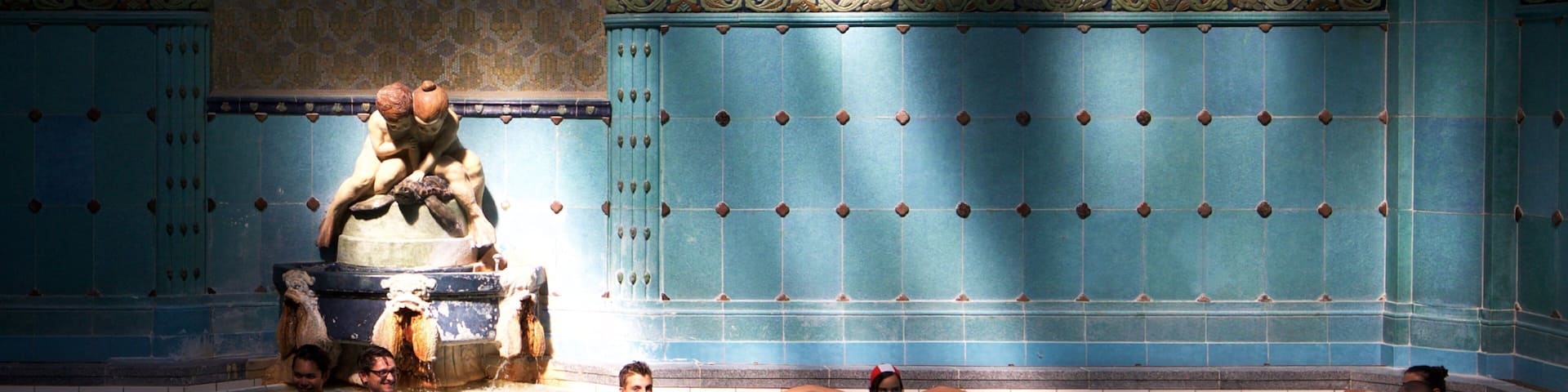 A swimming pool with a decorative fountain and tiled walls.