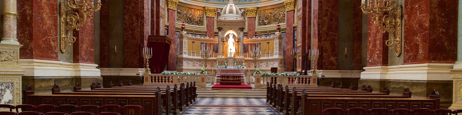 An ornate church interior with marble columns, a central altar, and a dome ceiling with frescoes.
