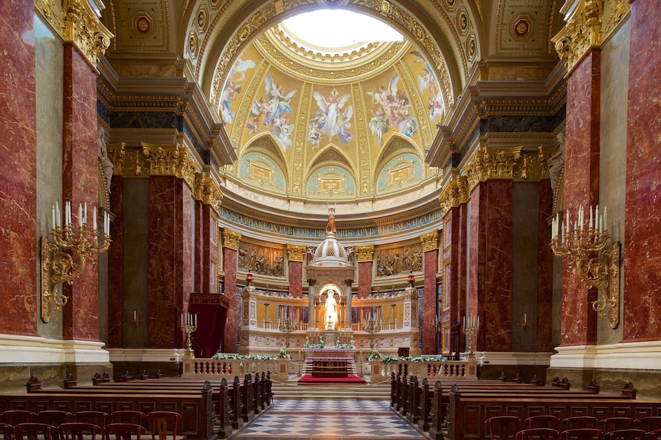 An ornate church interior with marble columns, a central altar, and a dome ceiling with frescoes.