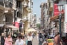 A bustling street with historic buildings, outdoor cafes, and a prominent hotel sign.