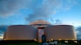 A large, modern building with a dome and two cylindrical structures.
