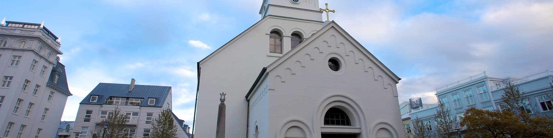 A white church with a clock tower and a weather vane.