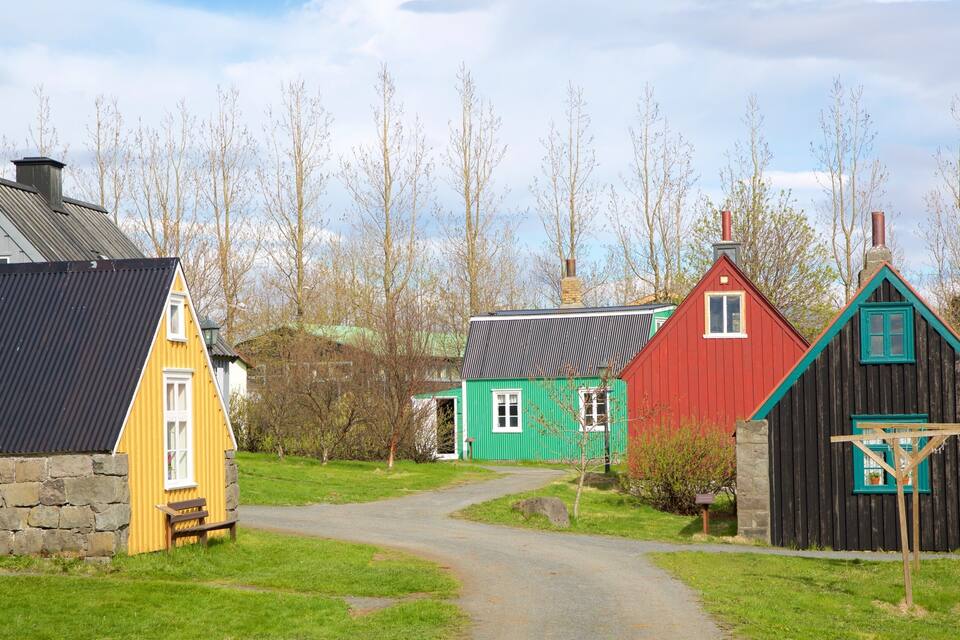 A rural village with colorful houses, a stone wall, and a narrow path.