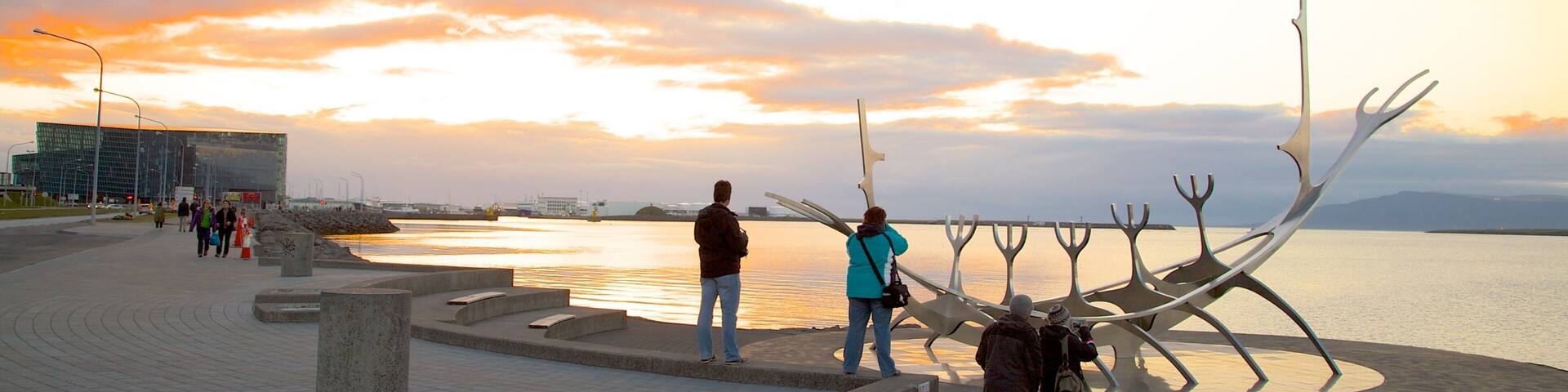 Une promenade en bord de mer agrémentée d’une sculpture moderne et offrant une vue sur le coucher de soleil.