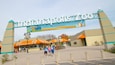 The entrance to the Indianapolis Zoo with a large sign and a parking lot.