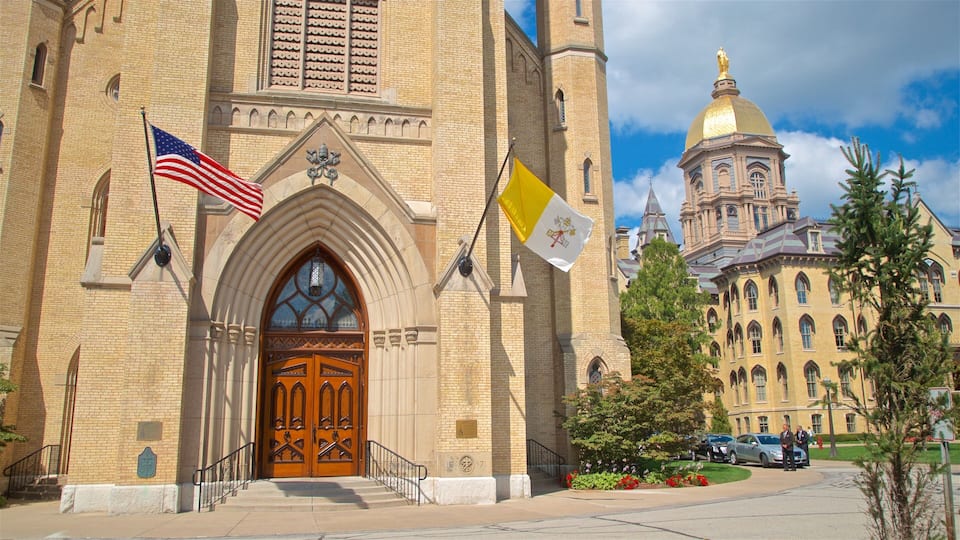 A historic building with a large wooden door, an American flag, and a flag with a coat of arms.