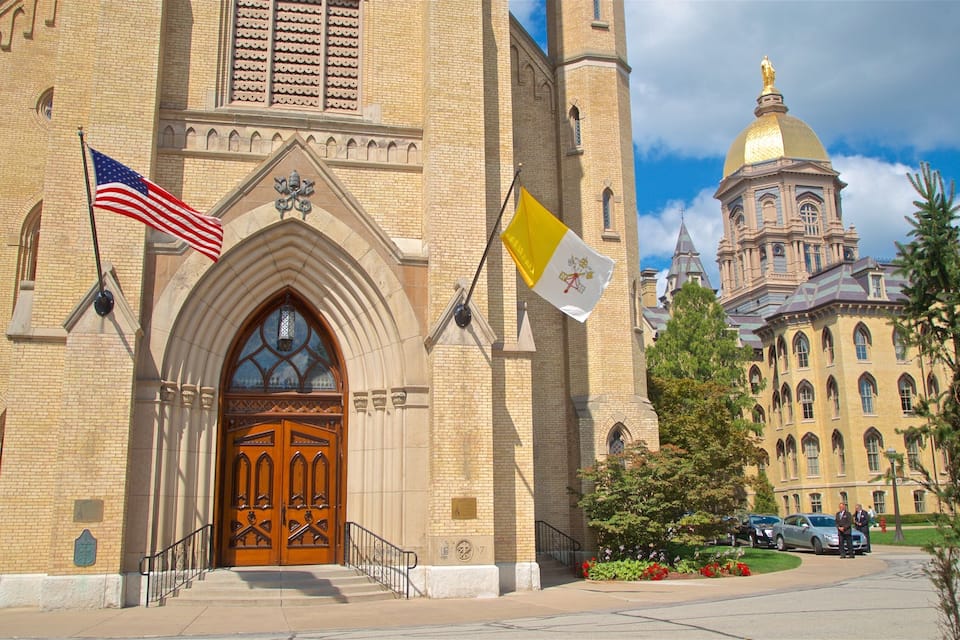 A historic building with a large wooden door, an American flag, and a flag with a coat of arms.