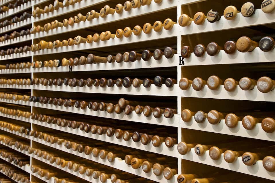 A wall of wooden baseball bats organized by size and weight.
