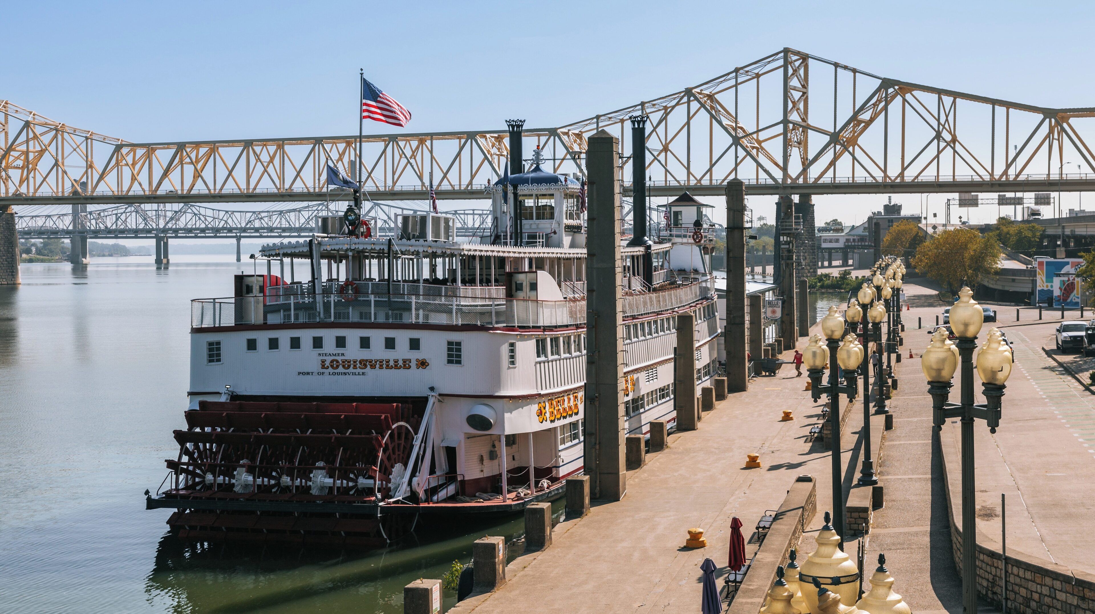 Belle of Louisville docked at the waterfront in Downtown Louisville, Kentucky, with a clear sky and bridges in the background