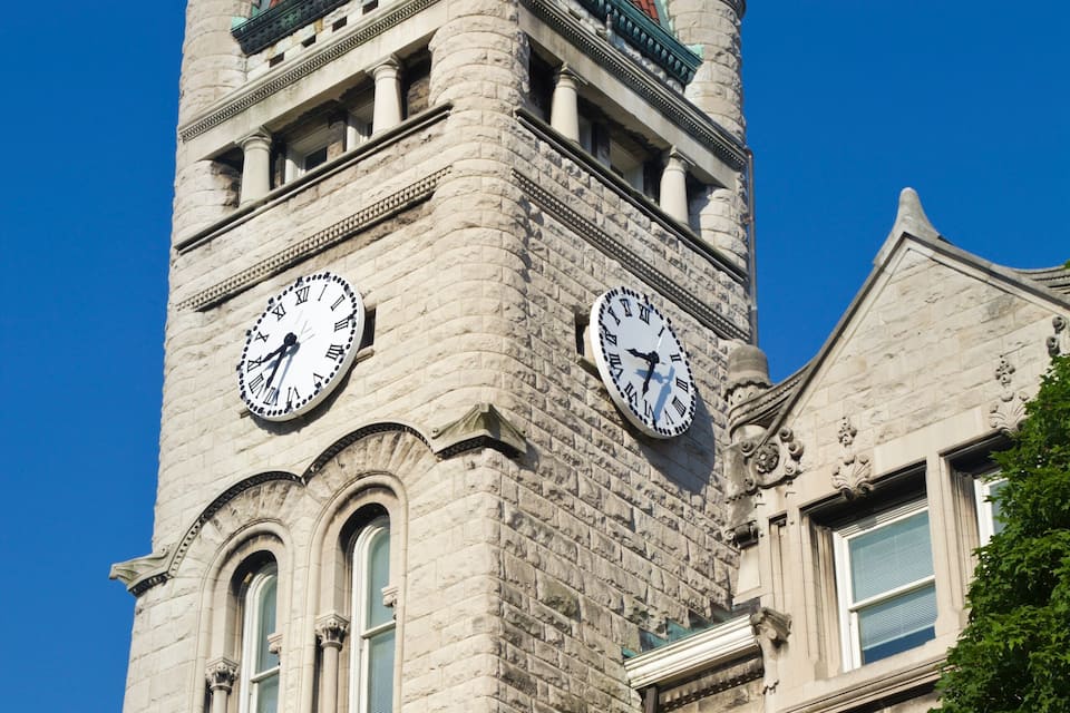 Een historisch gebouw met een klokkentoren, herkenbaar aan het rode pannendak en de stenen gevel.