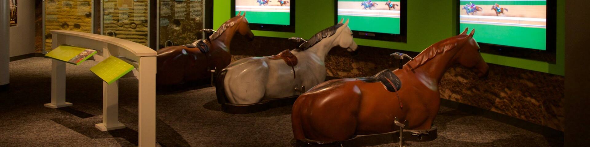A horse racing exhibit with mounted jockeys and a racing track display.